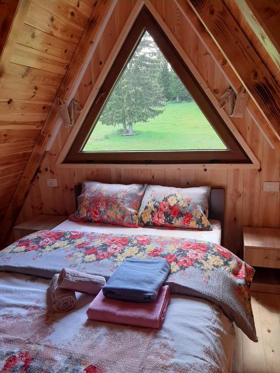 a bed in a room with a large window at Wooden cottage Podgora in Žabljak