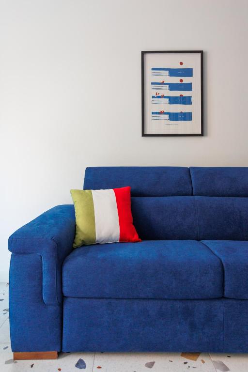 a blue couch with a colorful pillow on it at Dimore Italiane - Private Suites in Corralejo