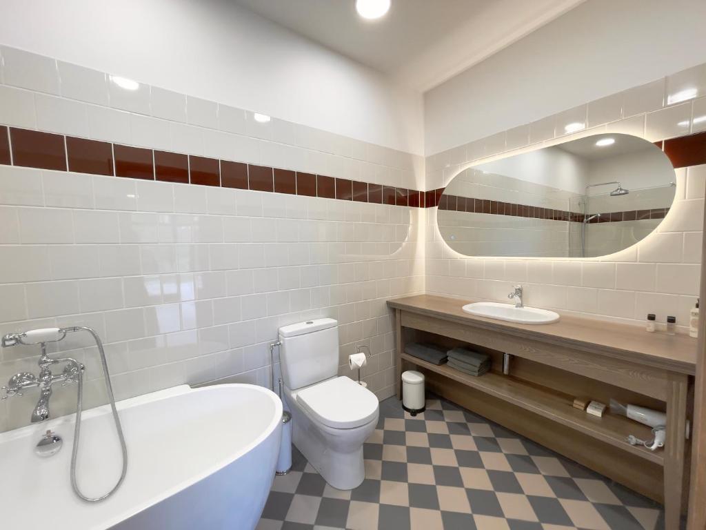 a bathroom with a tub and a toilet and a sink at Karlamuiza Country Hotel in Kārļi