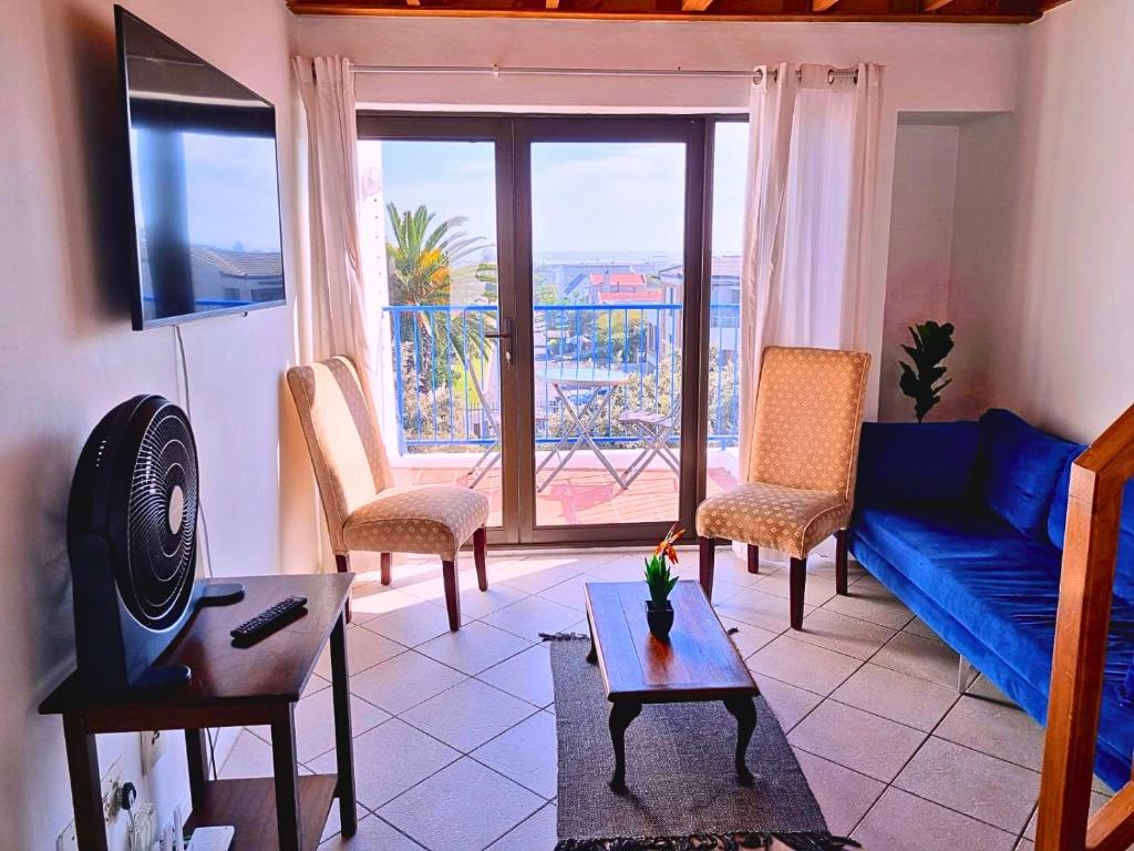 a living room with a blue couch and a table at 24 Arniston Village, Melkbosstrand in Melkbosstrand