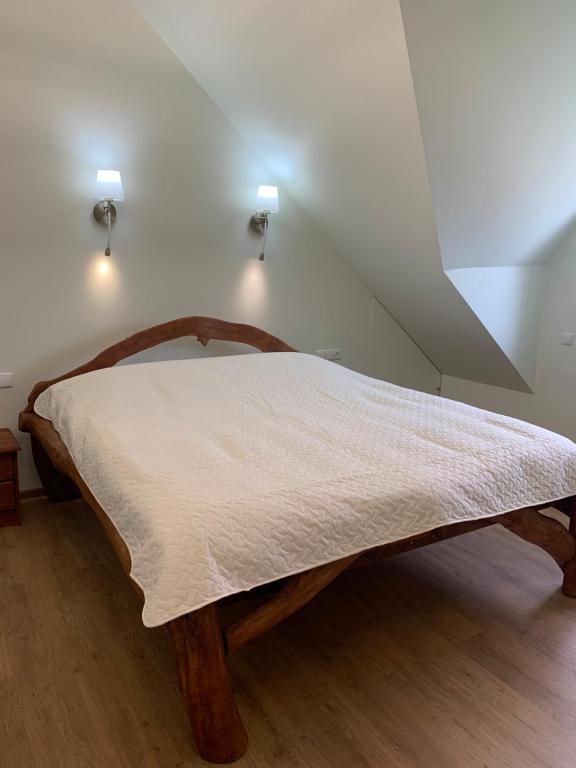 a bedroom with a wooden bed with white sheets at Green House in Ramučiai