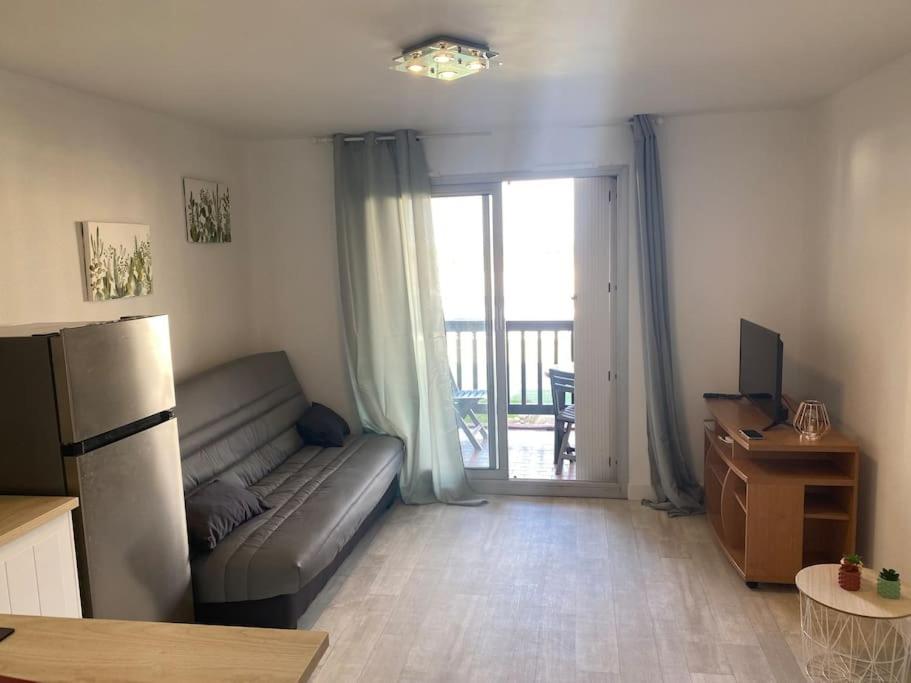 un salon avec un canapé et une porte coulissante en verre dans l'établissement Charmant studio île des pêcheurs piscine tennis, au Cap d'Agde