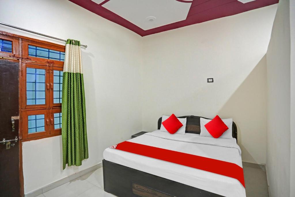 OYO Flagship Hotel Midtown 2 في نويدا: غرفة نوم بسرير ومخدات حمراء ونافذة