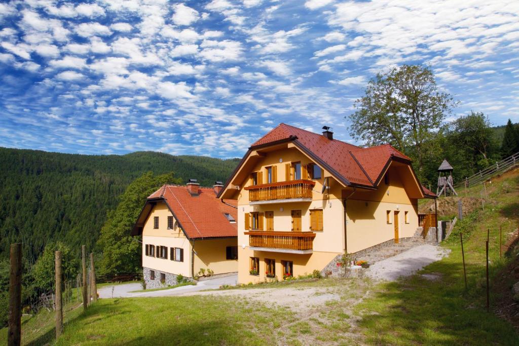 une grande maison avec un toit rouge sur une colline dans l'établissement Tourist Farm Arbajter, à Resnik