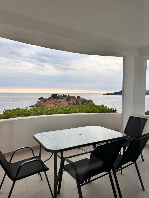 a table and chairs on a balcony with a view of the ocean at Villa Milan in Sveti Stefan