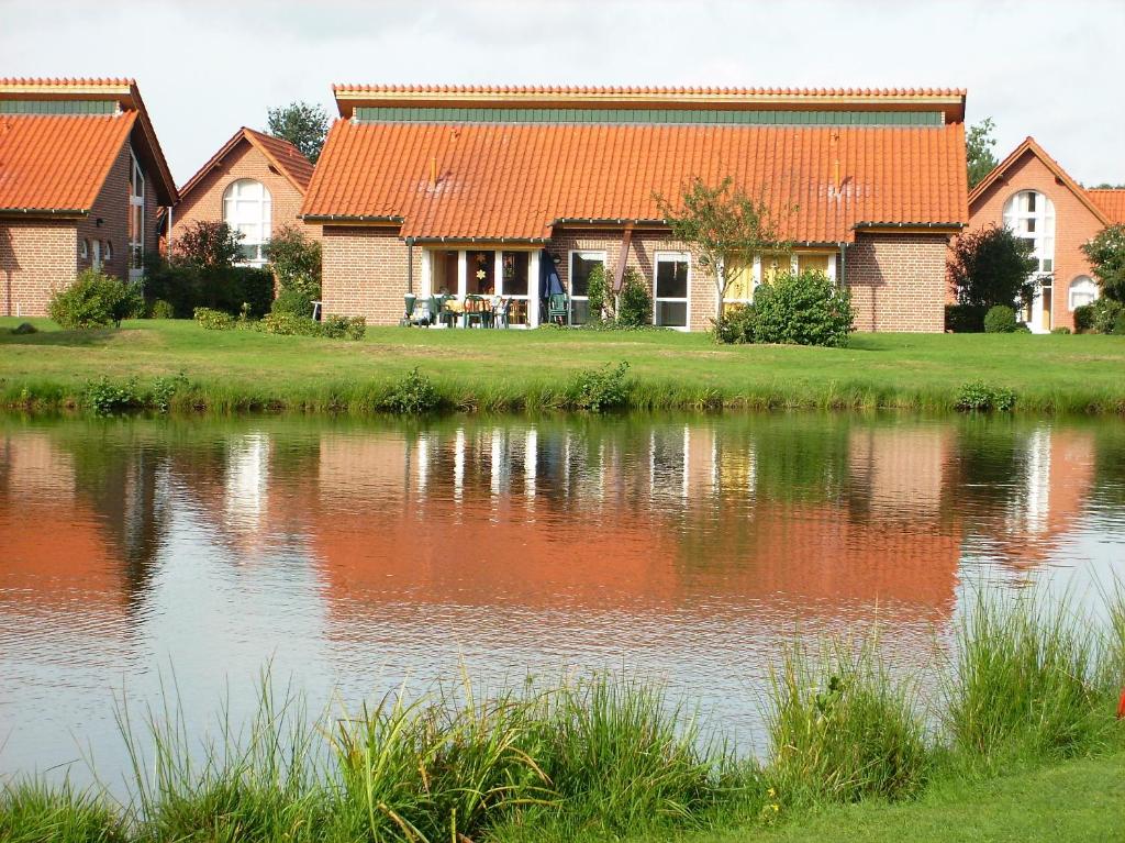 ein Haus mit einem orangenen Dach neben einem See in der Unterkunft Ferienhaus im Golfpark in Haren