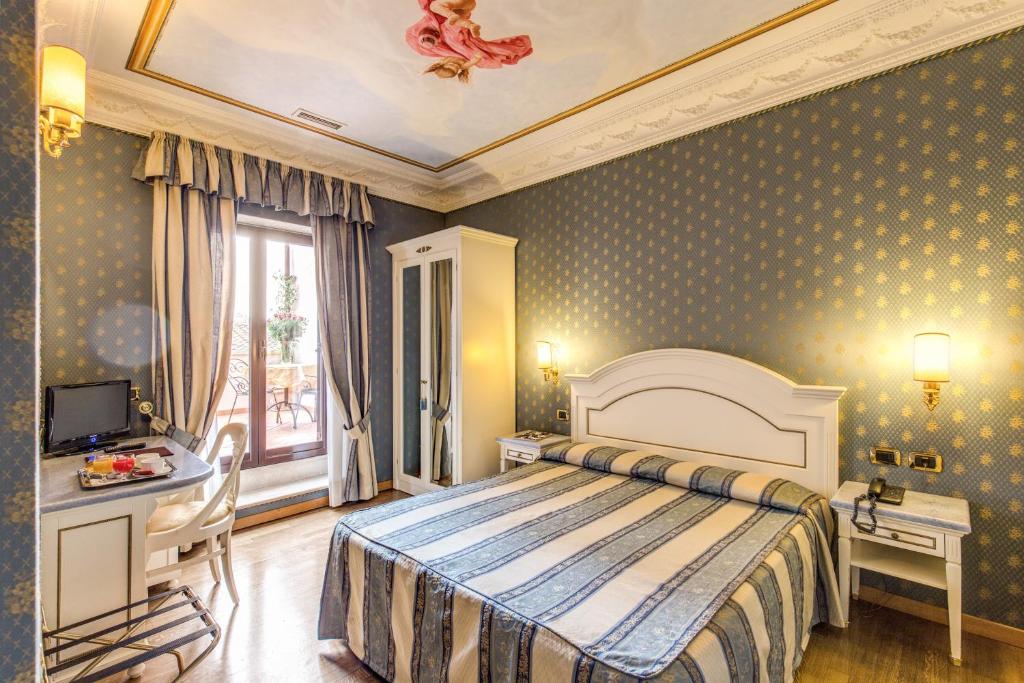 a bedroom with a bed and a desk and a window at Hotel La Lumiere Di Piazza Di Spagna in Rome