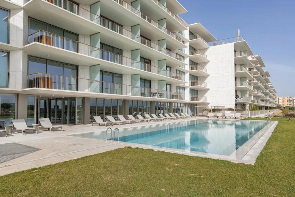 a large apartment building with a swimming pool and chairs at Bayline- Beachfront and Pool in Armação de Pêra