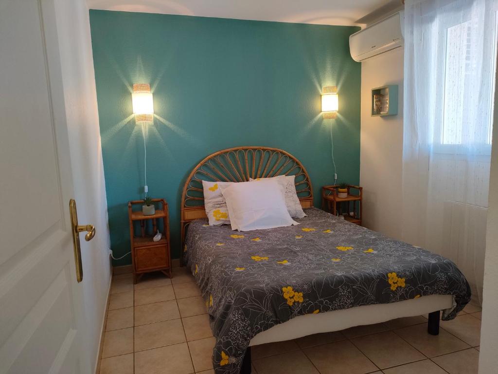 sypialnia z łóżkiem i niebieską ścianą w obiekcie appartement en rez-de-chaussée et terrasse sans vis a vis w mieście Canet-en-Roussillon