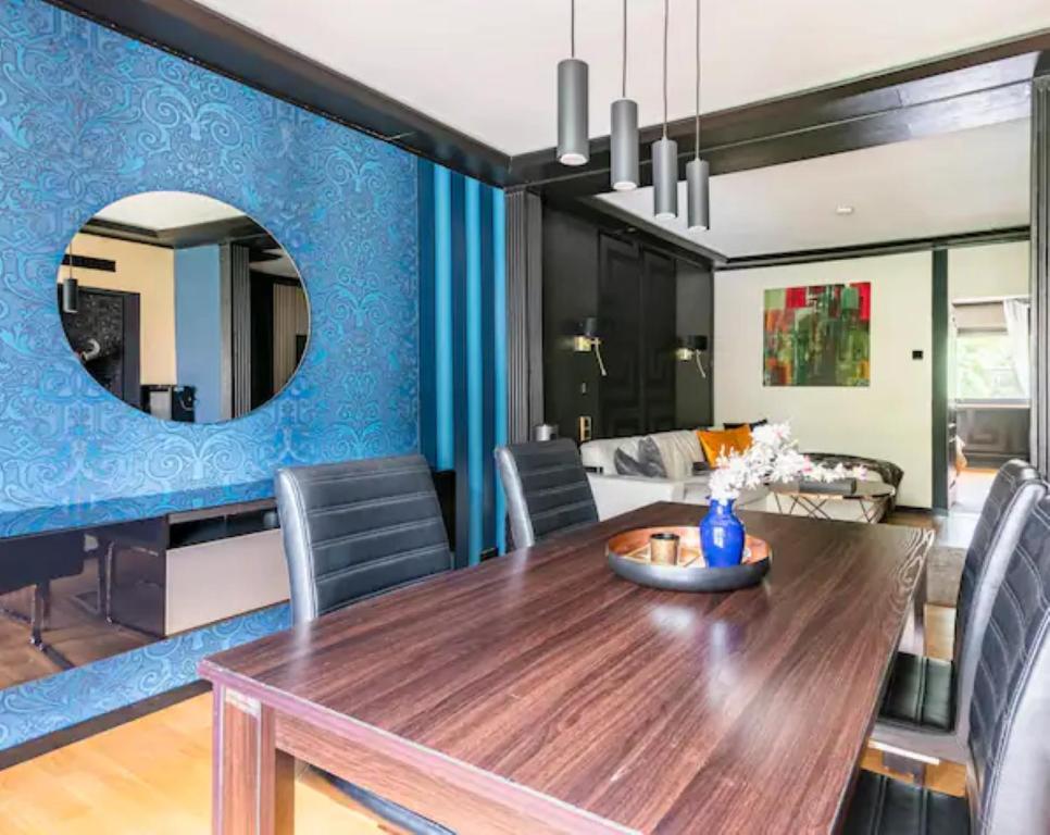 Miet-Kamp ruhig, zentral, nahe Messe, ausgefallenes design 2 Schlafzimmer في برلين: غرفة طعام مع طاولة خشبية والجدار الأزرق