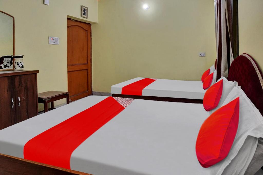 1 dormitorio con 2 camas y almohadas rojas en OYO Flagship 81231 Urmila Guest House en Bodh Gaya