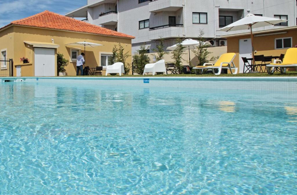 a large blue swimming pool in front of a building at Pontes Guest House in Arcozelo