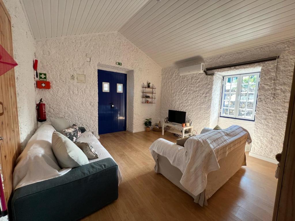 ein Wohnzimmer mit Sofa und Fernseher in der Unterkunft Vacas Felizes Villas in Ribeira Grande