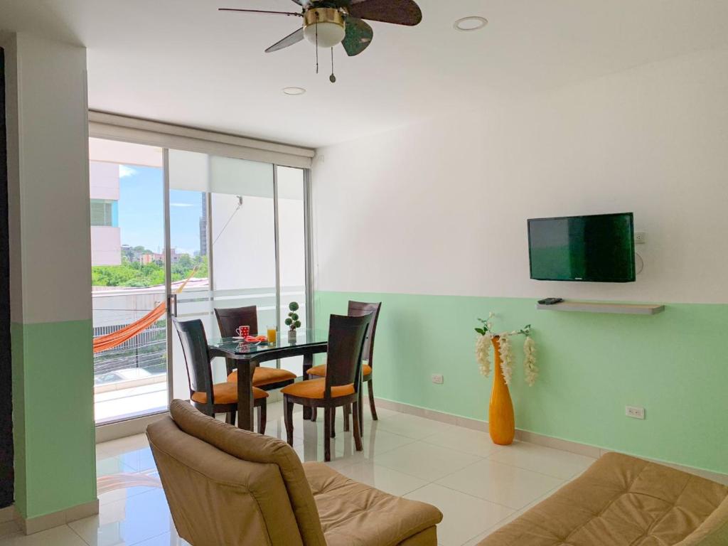 sala de estar con mesa, sillas y TV en Hotel Cabreromar By GEH Suites en Cartagena de Indias