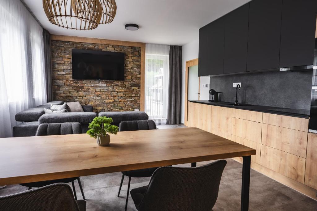 uma cozinha e sala de estar com uma mesa de madeira em Luxusní Apartmán Domovjanka - SKALKA FAMILY em Bílá