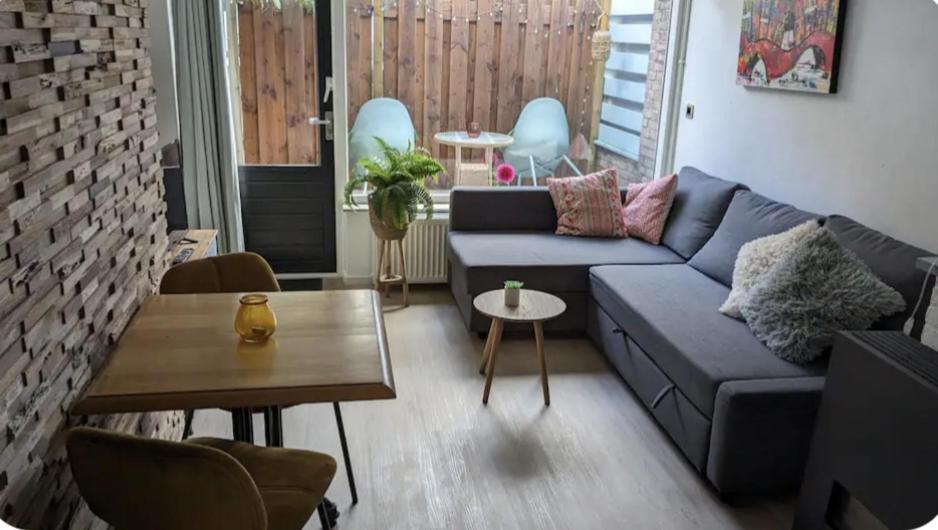 Una sala de estar con un sofá azul y una mesa. en zomerhuis in Wijk aan Zee! 2 pers, en Wijk aan Zee