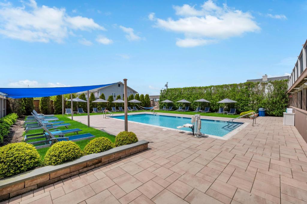a pool at a hotel with umbrellas and bushes at The Ocean Resort Inn in Montauk