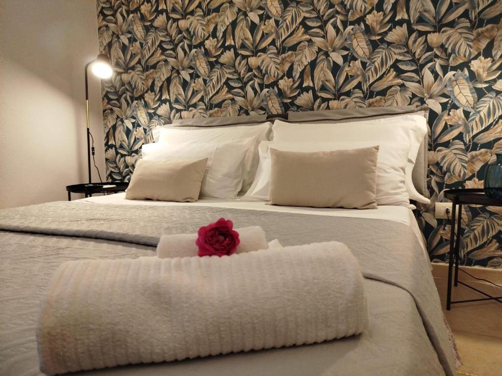 Un dormitorio con una cama con una flor roja. en Cuore Barocco, en Noto