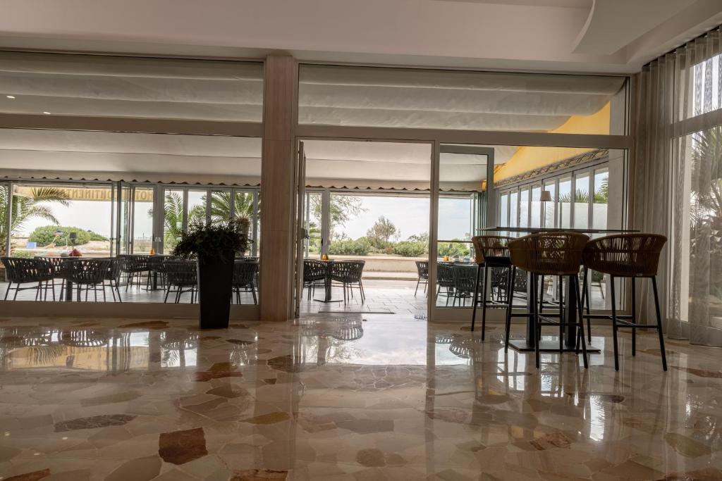a dining room with tables and chairs and windows at Hotel Continental in Caorle