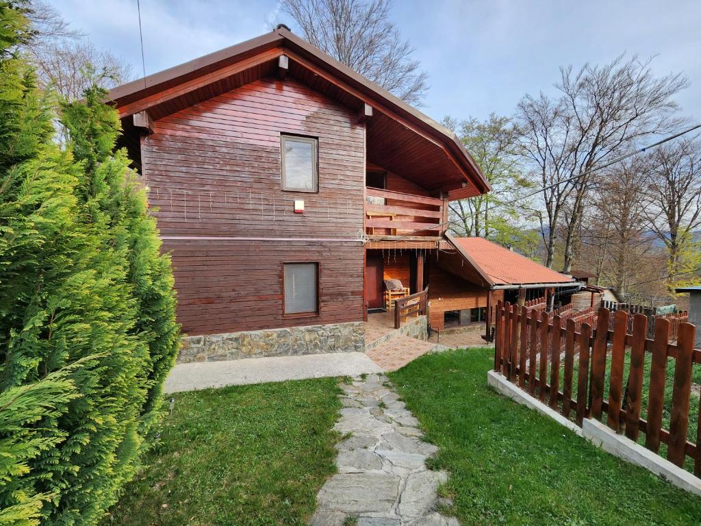 a wooden house with a fence next to a yard at Chalet Luna Parang in Petroşani