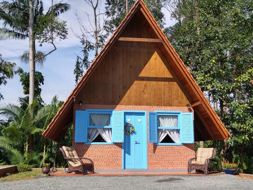 uma pequena casa com um telhado alto e uma porta azul em Chalé Bienen Garten em Pomerode
