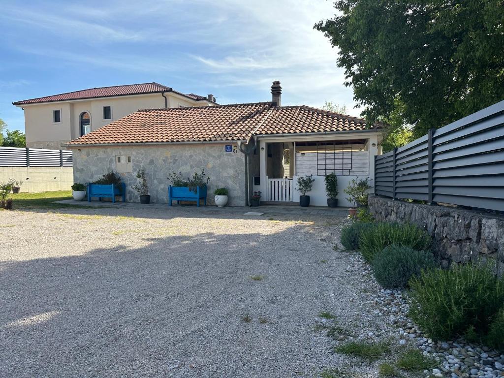 a small white house with a gate and blue chairs at Casa Mio in Malinska