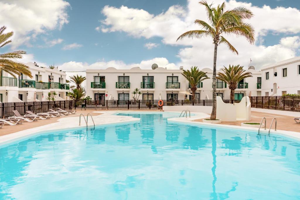 una grande piscina con palme e edifici di Flor de Las Dunas pools wifi tennis bikes for free a Corralejo