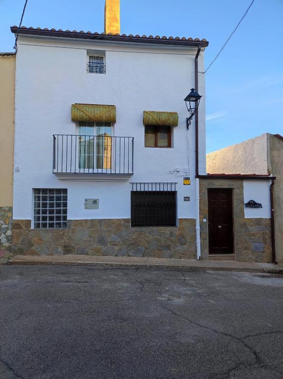 a white building with a balcony on a street at El Romeral in Fuenterrobles