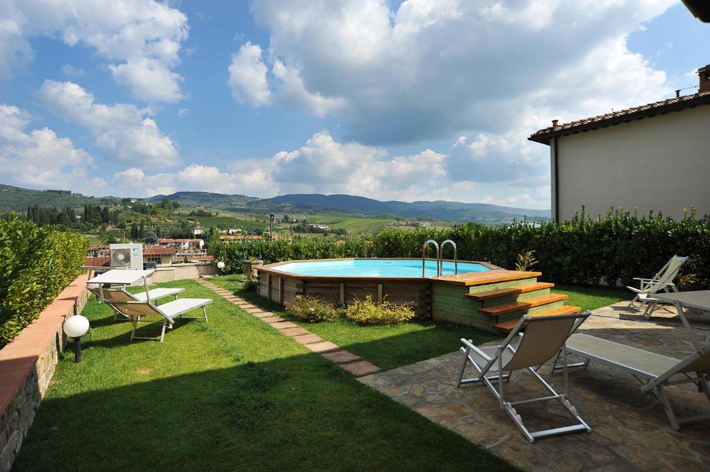 un patio trasero con una piscina con sillas y una mesa en Residenza Le Grillaie, en Greve in Chianti