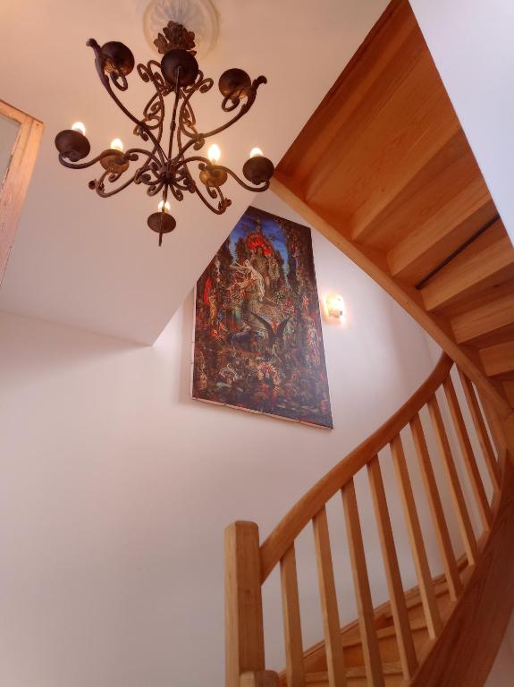 un tableau sur un mur à côté d'un escalier avec un lustre dans l'établissement Gîte groupe cycliste via rhona Les Capucines, à Saint-Vallier