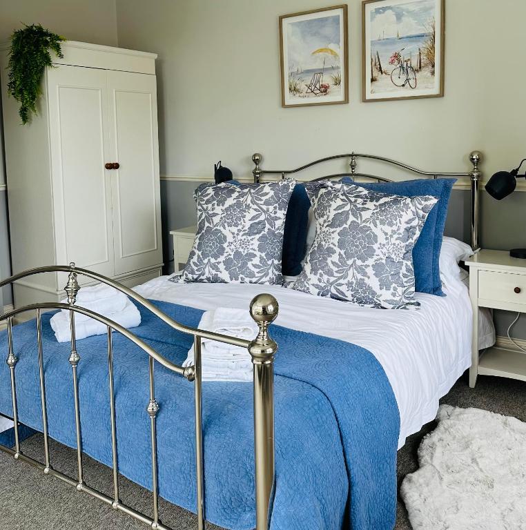 a bedroom with a bed with blue and gray pillows at Bettys in Hunstanton