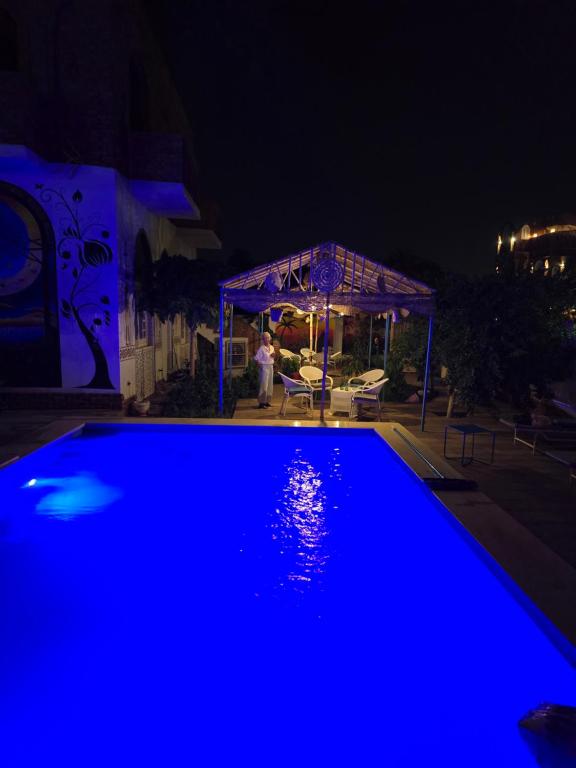 - une piscine bleue la nuit avec un kiosque dans l'établissement Flower of Life, à Louxor
