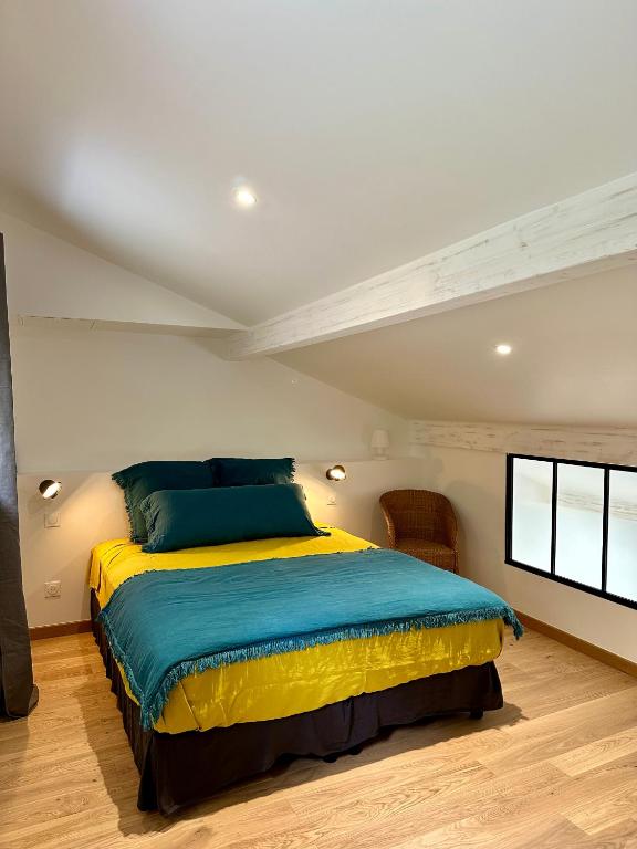 - une chambre dotée d'un lit avec une couverture bleue et jaune dans l'établissement Maison Jasmin, à Gruissan