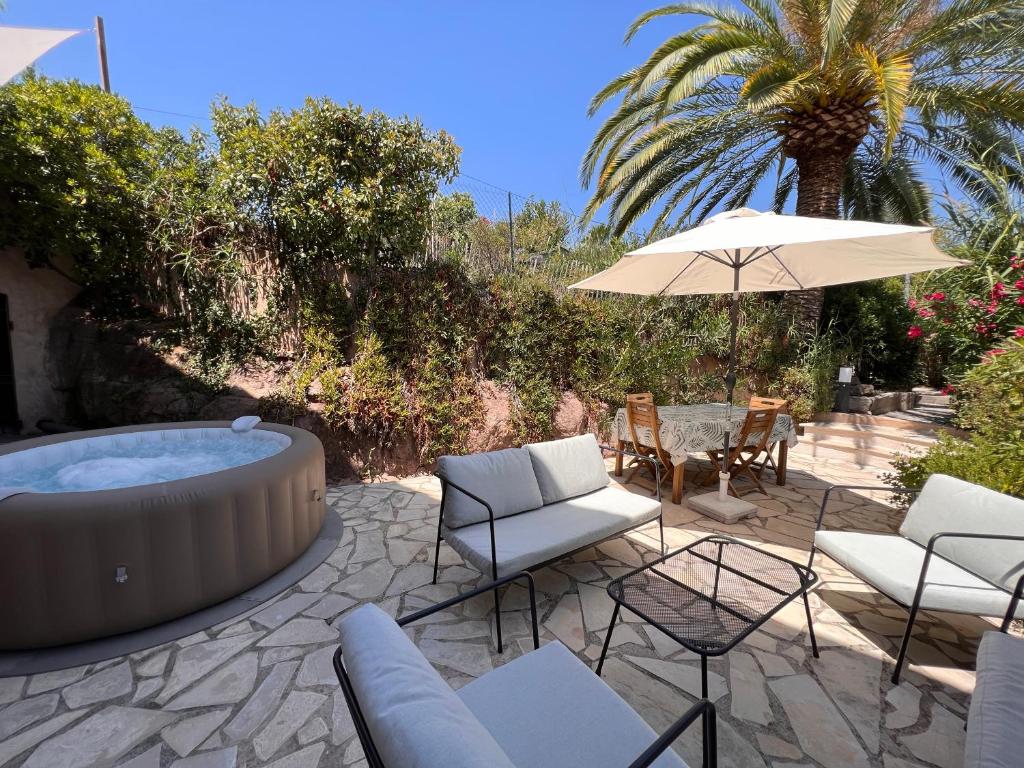 a patio with a hot tub and chairs and an umbrella at SIMONE, Appartement maison, quartier calme, grande terrasse, SPA, barbecue, 2 chambres in Fréjus