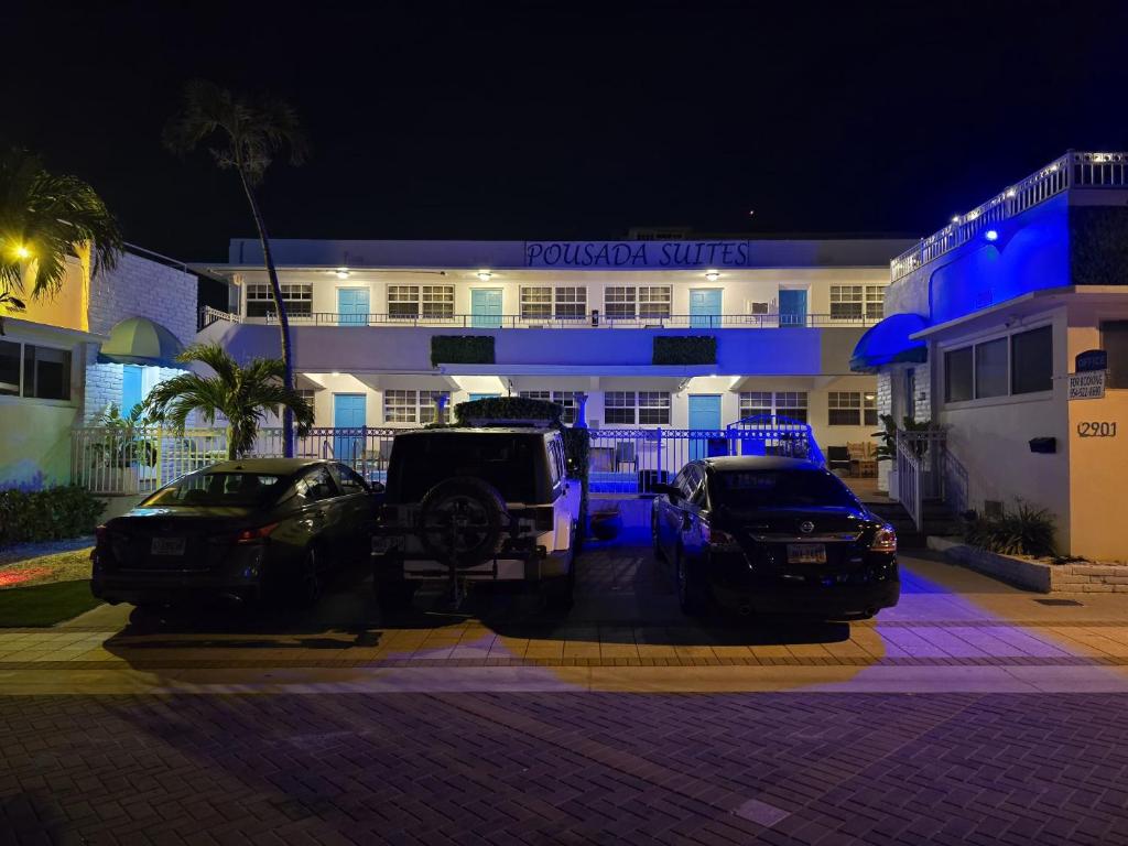 dos autos estacionados frente a un edificio por la noche en Pousada suites, en Hollywood