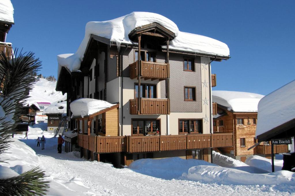 a large building covered in snow with people walking around it at Familienhotel Garni Sporting in Bettmeralp