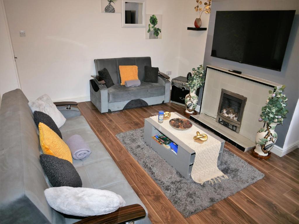 een woonkamer met een bank en een open haard bij Comfort Home From Home Bolton Central Hilden St - Sleeps - 10 in Bolton