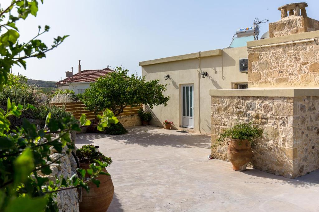 Eliana's Stone House في Benoudhianá: ساحة منزل بها نباتات الفخار