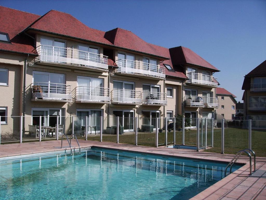 un edificio con una piscina di fronte a un edificio di Green Garden a De Haan