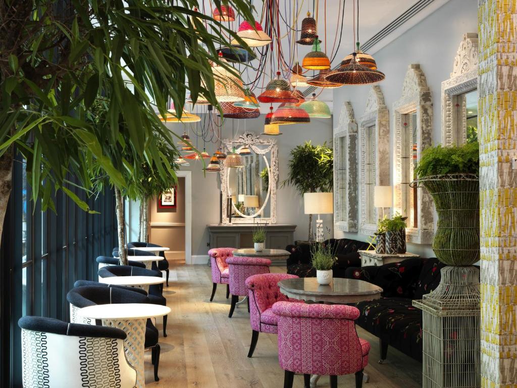 a restaurant with pink chairs and tables and plants at Ham Yard Hotel, Firmdale Hotels in London