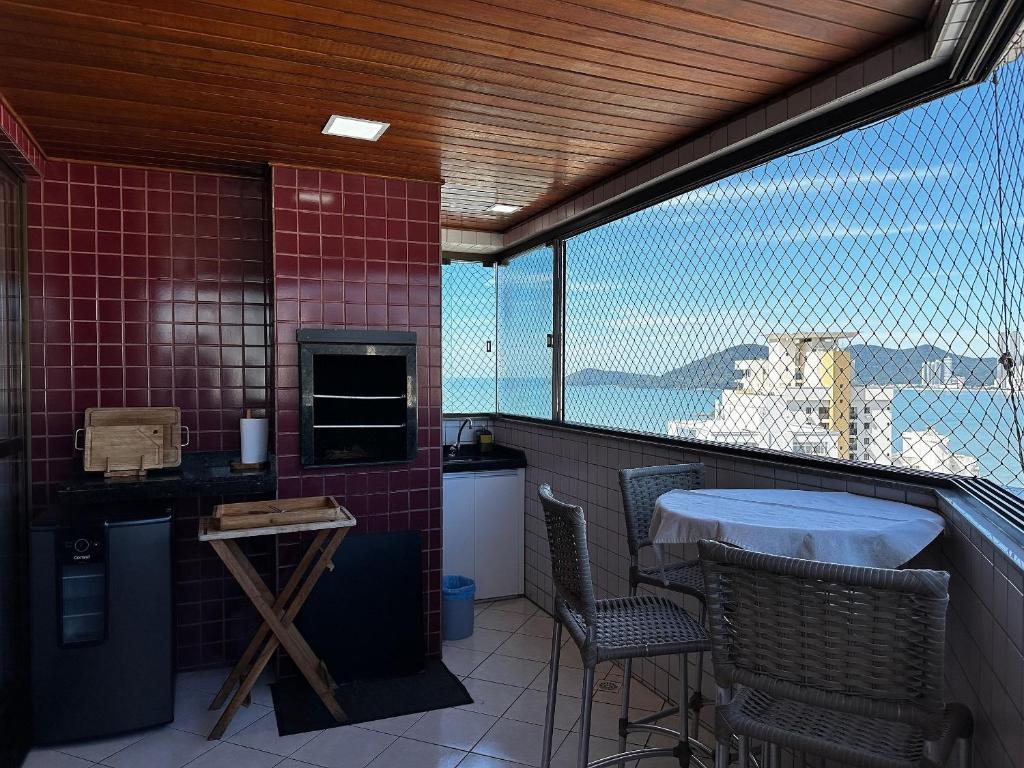 a balcony with a table and chairs and a view at CT01- Vista mar| Telas Proteção| Churrasq, Garagem in Balneário Camboriú