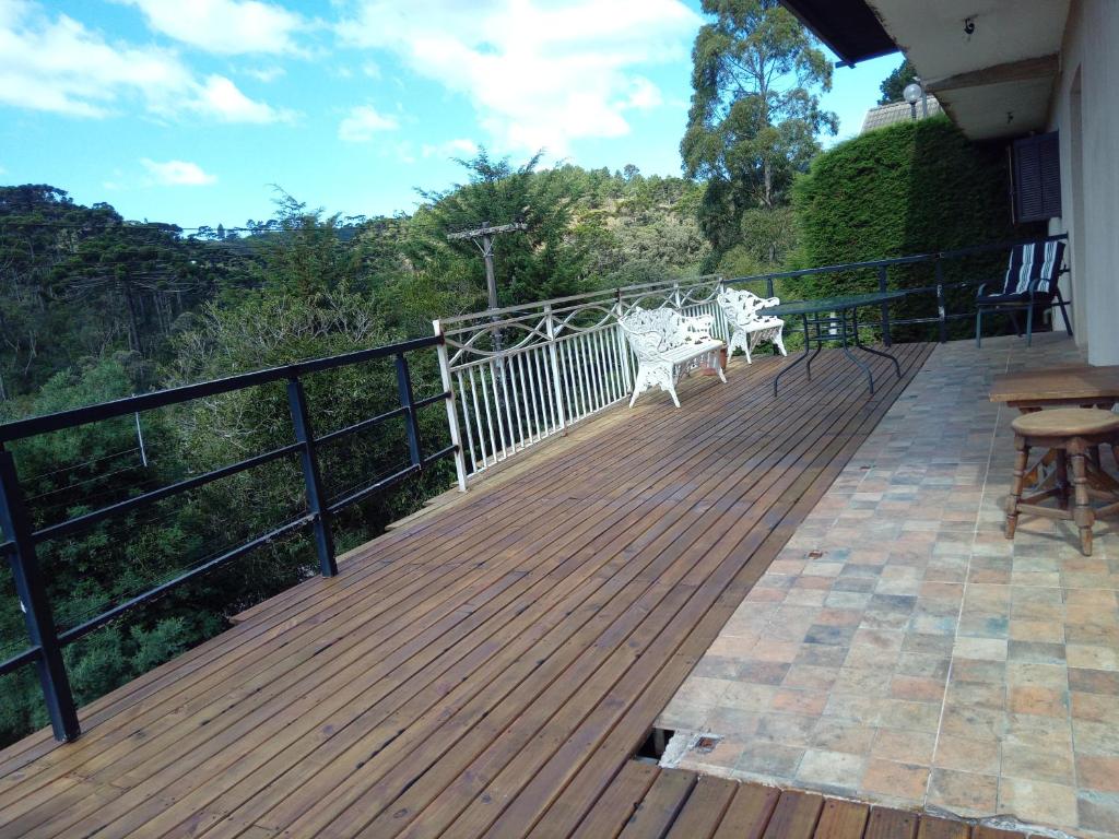 a wooden deck with two chairs and a table at Casa dos Neves in Campos do Jordão