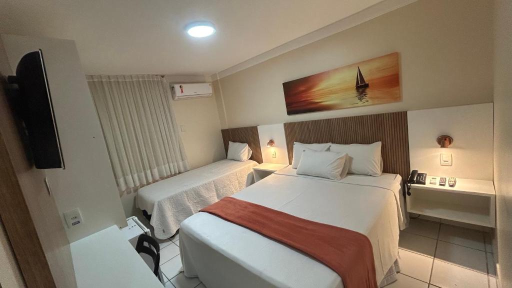 a hotel room with two beds and a television at Mar de Ponta Negra in Natal