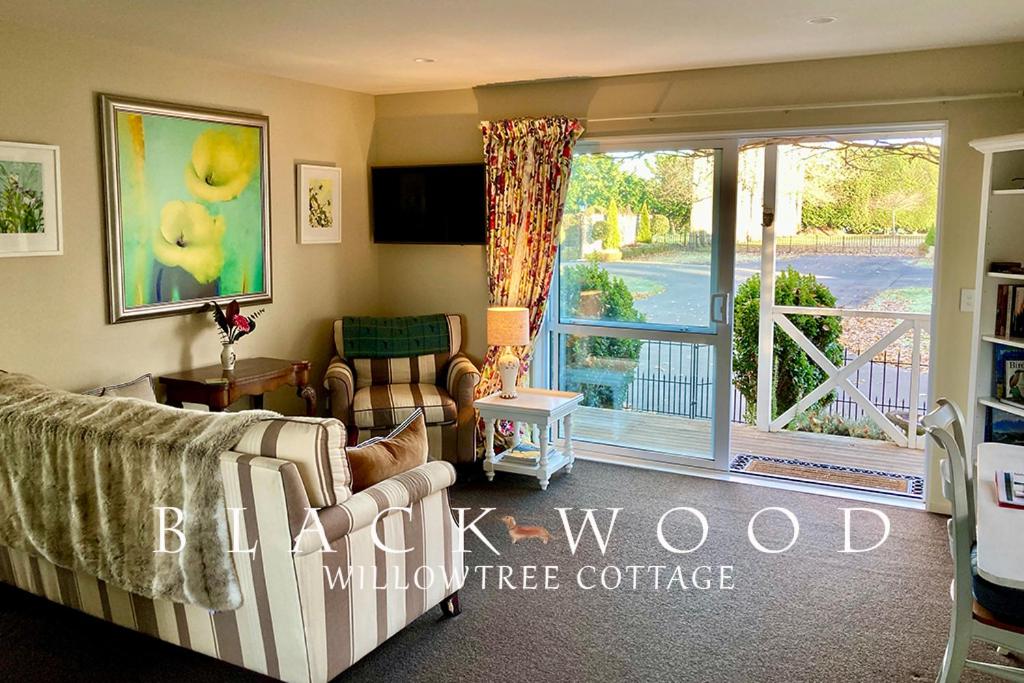 a living room with a couch and a sliding glass door at Willow Tree Cottage in Lincoln