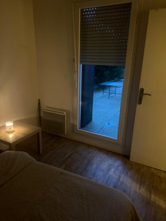 - une chambre avec une porte donnant sur une terrasse avec une table dans l'établissement Stade de France métro RER, à Aubervilliers