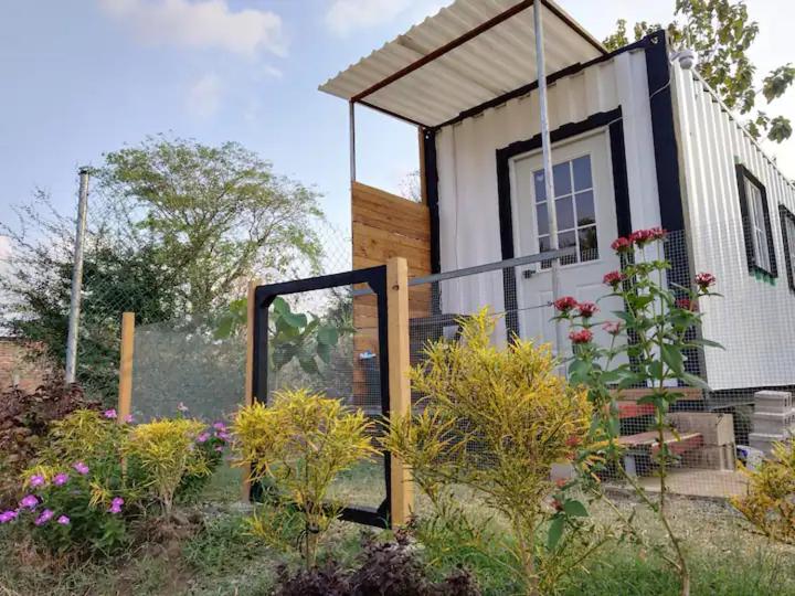 a small house with a garden in front of it at Countryside AC Container House in Sonsonate