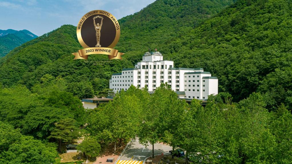 um grande edifício branco com uma grande placa e uma grande montanha em KensingtonHotel Seorak em Sokcho