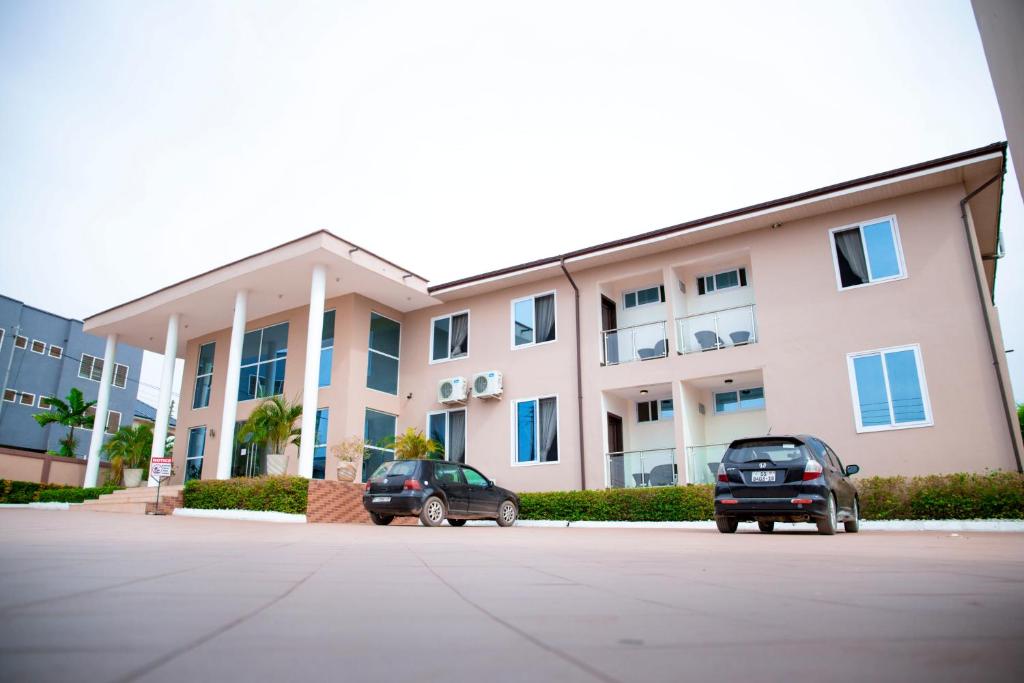 two cars parked in front of a large building at Cromer Apartment Hotel in Accra