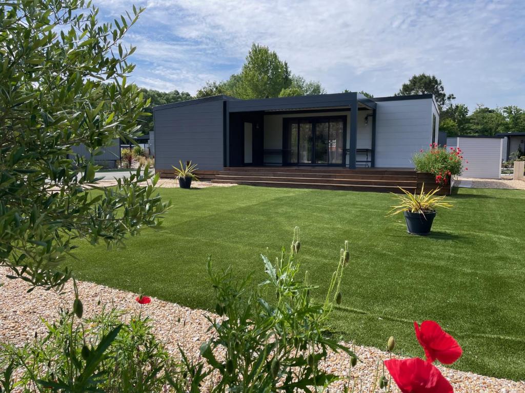 een modulair huis met een tuin met groen gras bij Cosy ecolodge with shared heated pool 10 from the beach in Les Mathes