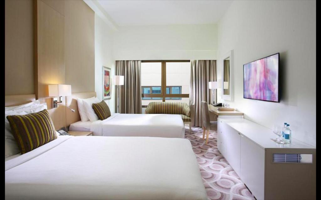 a hotel room with two beds and a couch at Metropolitain Dubai Hotel - Guest Room - UAE in Dubai